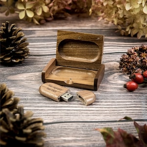 Könnte beinhalten: Ein USB-Stick aus Holz mit einer personalisierten Gravur in einer Holzkiste. Die Gravur lautet "Your engraver Your text".