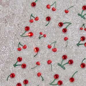 Pu&ograve; includere: Uno sfondo bianco con ciliegie rosse con steli verdi sparse sulla superficie.