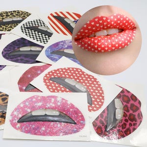 May include: A collection of temporary lip tattoos featuring various patterns including leopard print, checkerboard, red and white stripes, stars, galaxy prints, and red hearts, with one example shown applied to a pair of human lips.