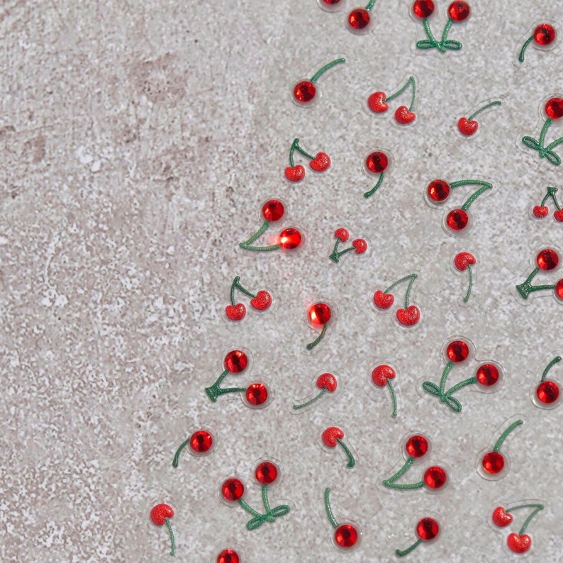Pu&ograve; includere: Uno sfondo bianco con ciliegie rosse con steli verdi sparse sulla superficie.
