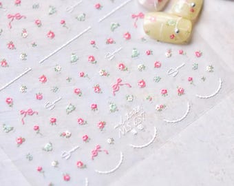 May include: Clear sheet of nail art stickers featuring small pink roses, green leaves, and white bows. The design includes white curved lines and the text "MS 637". The stickers are for nail decoration.