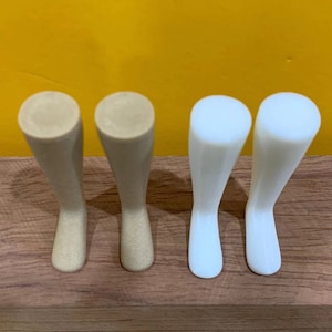May include: Four plastic doll legs, two are beige and two are white. The legs are all the same size and shape, and they are arranged in two pairs.