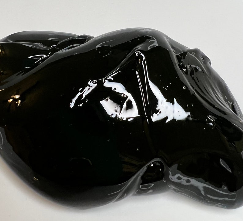 May include: A close-up of a black, gooey substance that resembles slime. The substance is shiny and has a smooth, wet texture.
