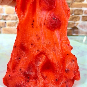 May include: Red slime with black specks, resembling a textured, gooey substance.