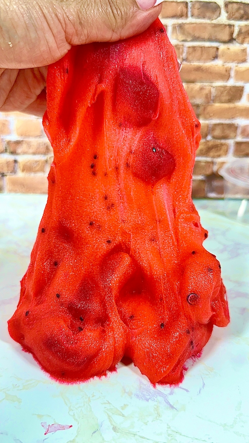 May include: Red slime with black specks, resembling a textured, gooey substance.