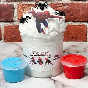 May include: A white slime in a clear jar with a Spider-Man label. The slime is topped with a Spider-Man figure and black spider figurines. The jar also includes a blue and a red lid.