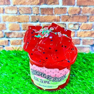 May include: A red watermelon-flavored ice slime in a clear plastic container with a red and green label that says "Watermelon Sorbet Ice Slime Do Not Eat!"