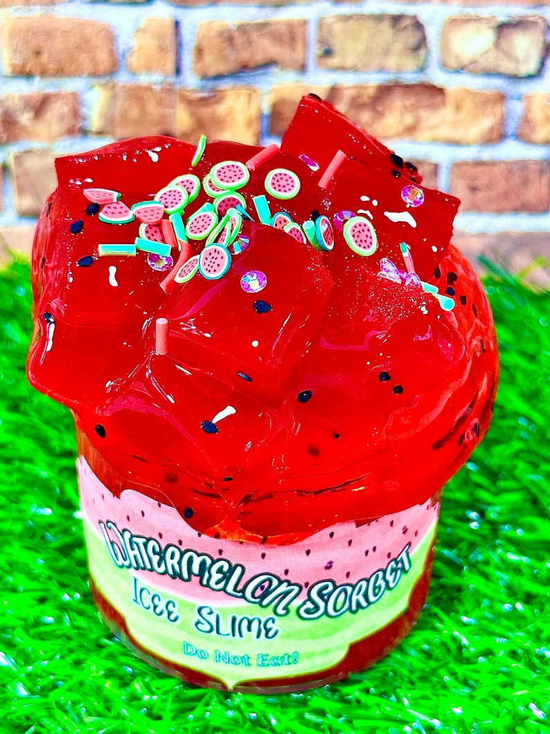 May include: Red watermelon-flavored slime with watermelon slice charms and sprinkles. The slime is in a clear container with a label that reads "Watermelon Sorbet Ice Slime Do Not Eat!"