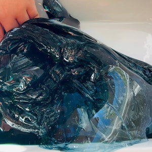 May include: A large amount of dark blue slime in a white container. The slime is very thick and gooey, and it has a slightly iridescent sheen.