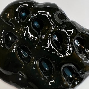 May include: Black slime with blue-grey orbs embedded inside. The slime is glossy and has a textured surface.