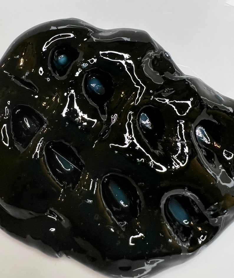 May include: Black slime with blue-grey orbs embedded inside. The slime is glossy and has a textured surface.