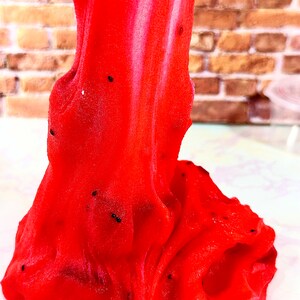 May include: Red slime with black specks, resembling a textured, gooey substance.