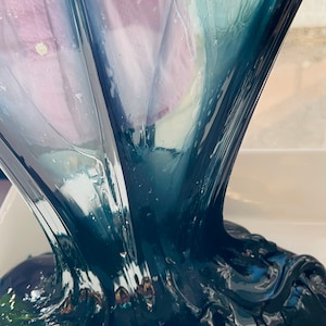 May include: A close-up of dark blue slime being poured into a white container. The slime is thick and gooey, and it has a slightly iridescent sheen.