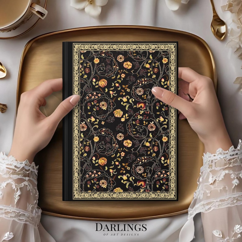 May include: A black journal with a floral design in gold, yellow, and brown tones. The journal is held on a gold tray. The text "DARLINGS OF ART DESIGNS" is visible at the bottom of the journal.
