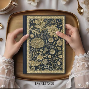May include: A dark blue notebook with a gold floral design and the text "Darlings of Art Designs" on the cover.