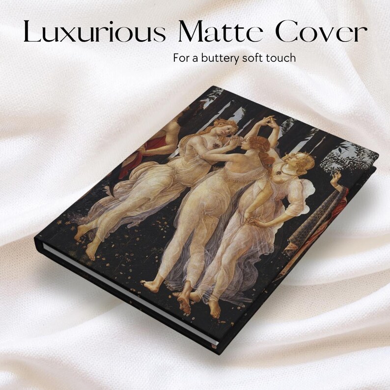 May include: A rectangular hardcover notebook featuring a matte finish with a reproduction of Botticelli's Three Graces painting on the front cover. The text "Luxurious Matte Cover" and "For a buttery soft touch" is printed above the notebook.