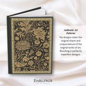 May include: A black journal with a gold floral design and the text "DARLINGS OF ART DESIGNS" on the cover. The journal is on a white fabric background.
