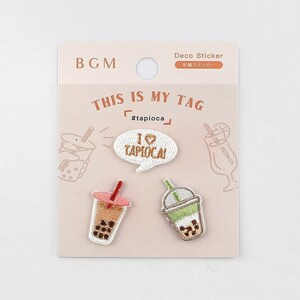 May include: A pack of embroidered deco stickers with bubble tea designs. The stickers include a speech bubble with "I ♡ tapioca" and two bubble tea cups. The packaging reads "THIS IS MY TAG" and "#tapioca".