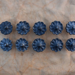 May include: Ten black metal drawer pulls with a floral design. Each pull has a raised center and a scalloped edge.
