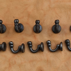 May include: Ten black cast iron hooks with a decorative design. The hooks are arranged in two rows of five.