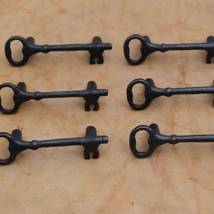 May include: Six black cast iron key-shaped drawer pulls. Each pull has a keyhole design and a decorative knob on the end.