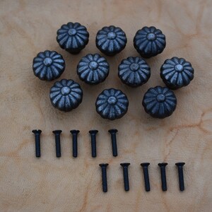Puede incluir: Diez pomos de armario de metal negro con un diseño floral decorativo y un acabado plateado. Los pomos vienen con veinte tornillos negros.