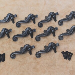 以下が含まれることがあります： 黒色の鋳鉄製のシーホースの引き出しノブ12個。ブラシ仕上げが施されています。ノブは3列4個ずつ配置されています。各ノブには背面にネジ穴があります。ノブには黒いネジ12個が付属しています。