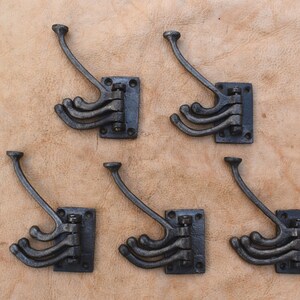 May include: Six black cast iron wall mounted hooks with a rectangular base and four hooks each. The hooks are in a staggered pattern.