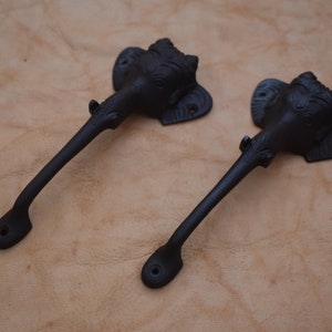 May include: Two black metal door handles with elephant head designs. The handles are about 10 inches long and have a simple, elegant design.
