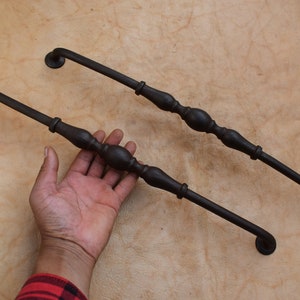 Könnte beinhalten: Zwei schwarze Metall-Schranktürgriffe mit dekorativem Design. Die Griffe sind etwa 25 cm lang.