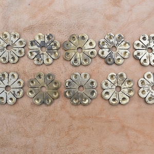 Könnte beinhalten: Zehn goldfarbene Metall-Conchos mit Blumenmuster. Jeder Concho hat 12 Zacken und eine kreisrunde Mitte.