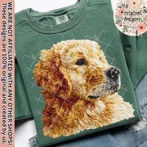 Könnte beinhalten: Ein salbeigrünes Sweatshirt mit einem detaillierten Stickbild eines Golden Retriever-Kopfes. Das Fell des Hundes ist in Gold-, Braun- und Cremetönen gehalten. Das Sweatshirt hat einen Rundhalsausschnitt und ein Comfort Colors-Etikett.
