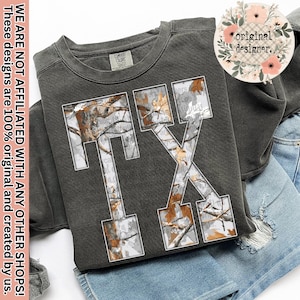 Könnte beinhalten: Dunkelgraues Sweatshirt mit den Buchstaben "TX" in weißer Umrandung, gefüllt mit einem Camouflagemuster. Das Sweatshirt ist auf Jeansshorts gefaltet. Der Text "WE ARE NOT AFFILIATED WITH ANY OTHER SHOPS! These designs are 100% original and created by us." befindet sich auf der linken Seite.
