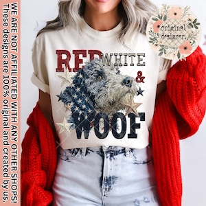 May include: Cream-colored t-shirt with a patriotic dog graphic. The design features a dog's face with an American flag pattern, stars, and the words "RED, WHITE & WOOF". The shirt also has the text "original designer."