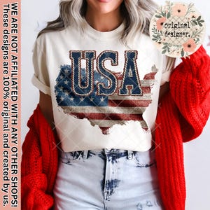 May include: Cream-colored t-shirt featuring a distressed American flag design in red, white, and blue, with the word "USA" in denim-style lettering. The shirt also has text that reads "WE ARE NOT AFFILIATED WITH ANY OTHER SHOPS! These designs are 100% original and created by us."