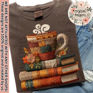 Può includere: T-shirt marrone con un disegno ricamato di una tazza di caffè su una pila di libri. La tazza e i libri presentano motivi patchwork e dettagli floreali. Il testo "original designer" è in un cerchio floreale.