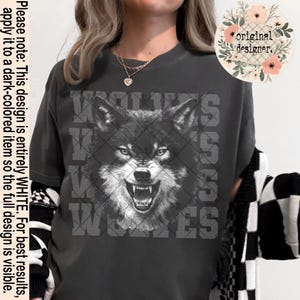 May include: Dark gray t-shirt featuring a detailed black and white wolf graphic with the word "WOLVES" in a block letter design. The shirt has a relaxed fit and short sleeves. The design is entirely white.