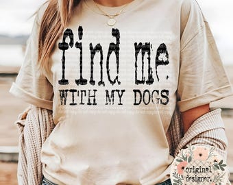 May include: A beige t-shirt with the text "Find me with my dogs" printed in black. The text has a distressed, vintage look.