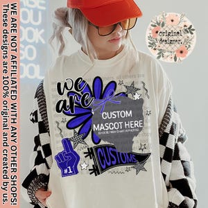 May include: Cream-coloured t-shirt with a large blue and black graphic design. The design includes the words "we are", "CUSTOM MASCOT HERE", and "CUSTOMS". The shirt also features a finger pointing up with the number "1".