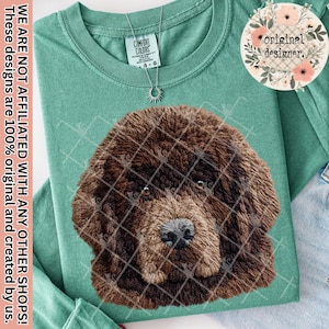 May include: A teal Comfort Colors long-sleeve shirt featuring a detailed brown dog face graphic. The shirt has a crew neck and a small silver necklace. The text "WE ARE NOT AFFILIATED WITH ANY OTHER SHOPS! These designs are 100% original and created by us." is printed on the left side.