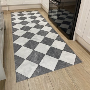 black and white checkerboard rug on oak floor in kitchen with white units
