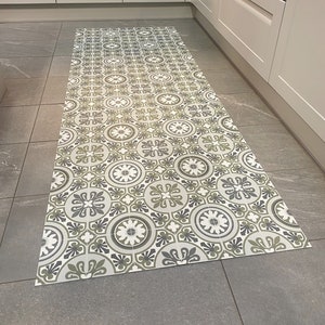 May include: A patterned kitchen rug with a geometric design in shades of green, white, and grey. The rug is made of a durable material and is perfect for protecting your floors from spills and dirt.