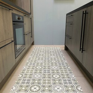 May include: A patterned kitchen runner rug with a geometric design in shades of grey, green, and white. The rug is placed in a kitchen with wooden cabinets and a light blue wall.