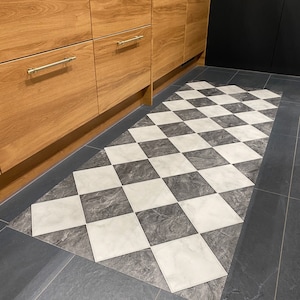 checkerboard vinyl rug on black tiled floor with wood units in kitchen