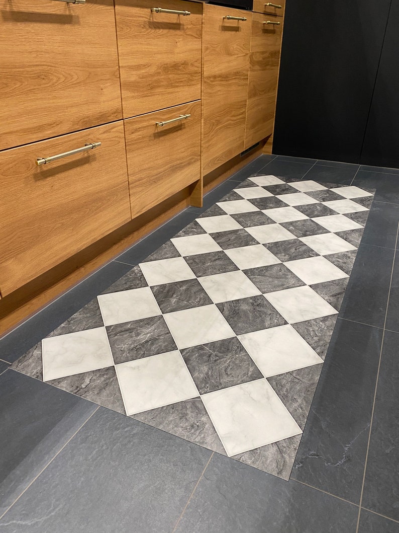 checkerboard vinyl rug on black tiled floor with wood units in kitchen