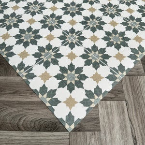 May include: A white, gray, and beige patterned floor tile with a geometric design. The tile is made of vinyl and has a textured surface.