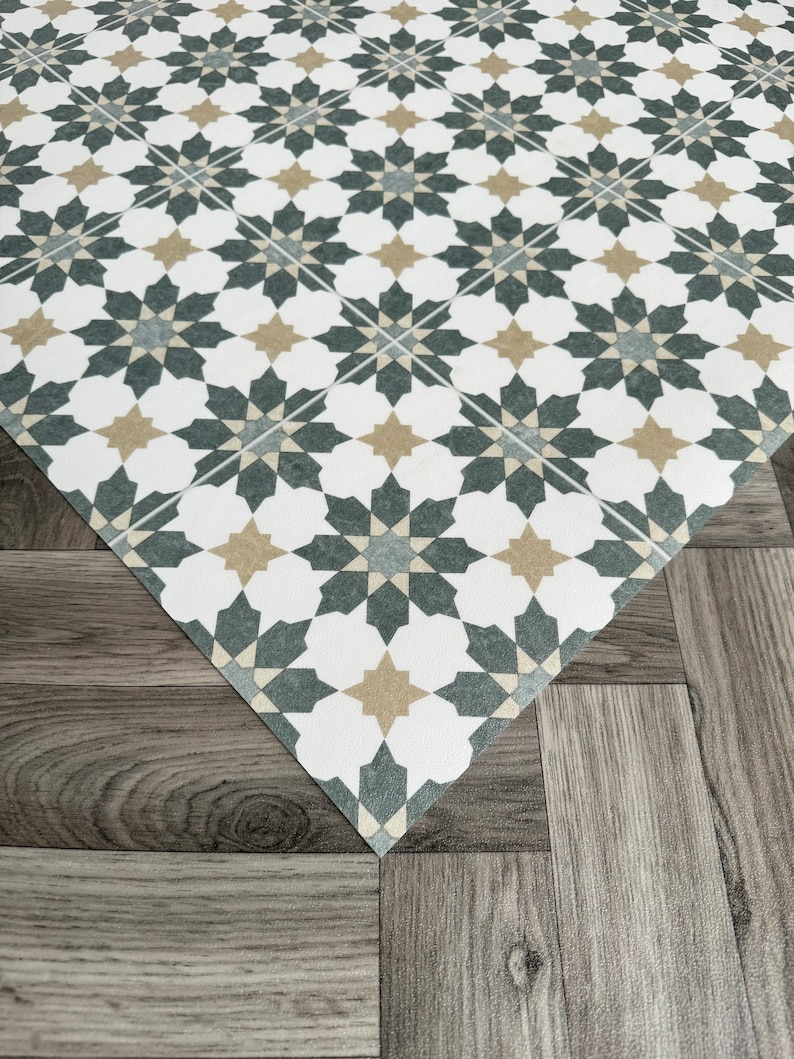 May include: A white, gray, and beige patterned floor tile with a geometric design. The tile is made of vinyl and has a textured surface.