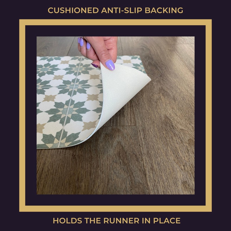 May include: Close-up of a green and beige patterned rug with a white, cushioned anti-slip backing. The backing is visible as the rug is being lifted up. "CUSHIONED ANTI-SLIP BACKING" and "HOLDS THE RUNNER IN PLACE" are written in black text on a gold background.