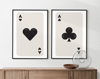 Könnte beinhalten: Zwei gerahmte Drucke von Spielkarten, jede mit einem schwarzen Ass mit einem Herz- und einem Kreuzsymbol. Die Karten sind auf einem hellbeigen Hintergrund und in Schwarz gerahmt.