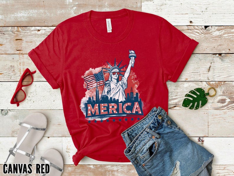 May include: Red t-shirt with a graphic of the Statue of Liberty, an American flag, and the word "MERICA". The shirt is paired with denim shorts, red sunglasses, and silver sandals. The words "CANVAS RED" are at the bottom.